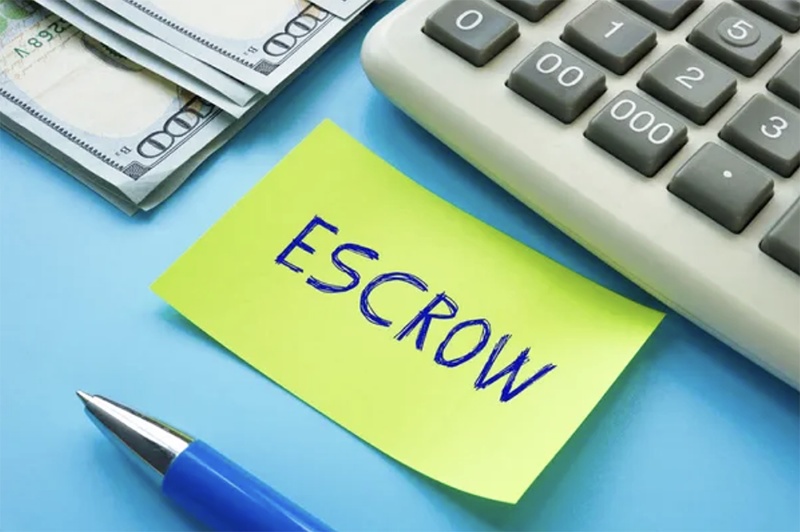 Escrow words written on a piece of paper with a pen next to a calculator and $100 bill - 1 (800) 880-7954